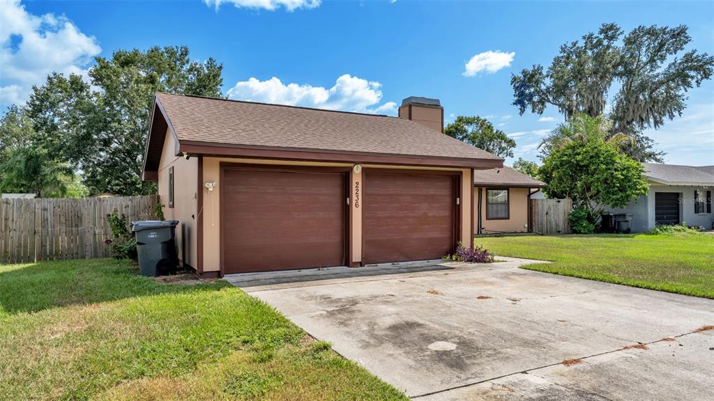 A detached two-car garage with brown doors and a shingled roof sits on a lawn — 2236 COUNTRY LOOP N, LAKELAND, FL
