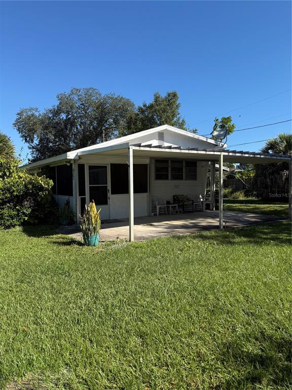 A white single-story house features a large covered patio and a grassy yard — 1985 ALADDIN COURT, ST CLOUD, FL