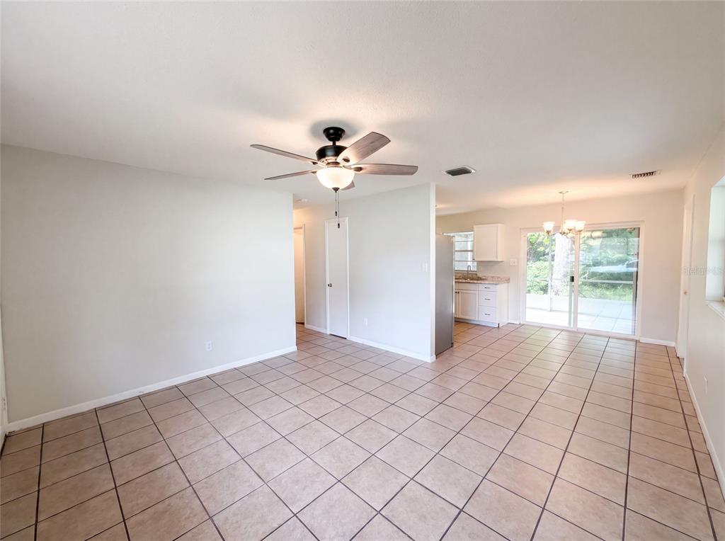 An open-concept room features light-colored tile flooring, a ceiling fan, and a kitchen area — 1735 JEFFERSON DRIVE, MOUNT DORA, FL