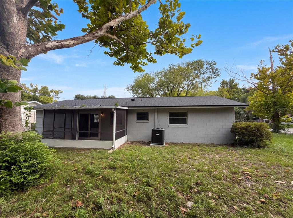 The exterior rear view of a single-story concrete block house with a screened-in porch — 1735 JEFFERSON DRIVE, MOUNT DORA, FL
