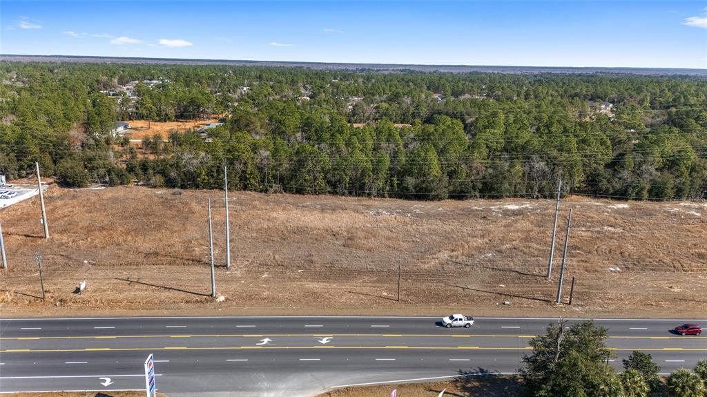 An aerial view shows a vacant, grassy lot situated alongside a multi-lane highway — SE MARICAMP ROAD, OCALA, FL