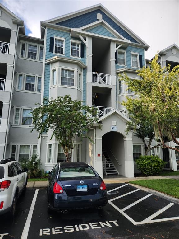 A multi-story apartment building exterior features blue siding, white trim, and a covered stairwell entrance — 5257 CANE ISLAND LOOP UNIT 302, KISSIMMEE, FL