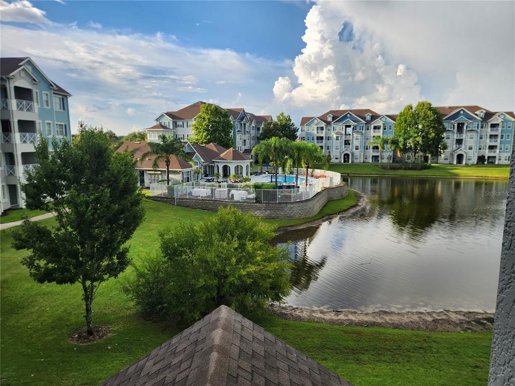 An elevated view of an apartment complex featuring a swimming pool, pond, and green space — 5257 CANE ISLAND LOOP UNIT 302, KISSIMMEE, FL