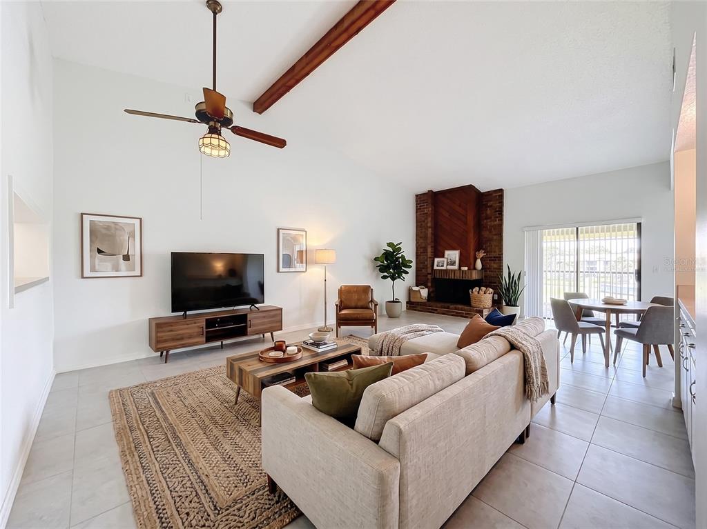 A living room with a vaulted ceiling, exposed wood beam, brick fireplace, and tile flooring — 15 ESCONDIDO COURT UNIT 148, ALTAMONTE SPRINGS, FL