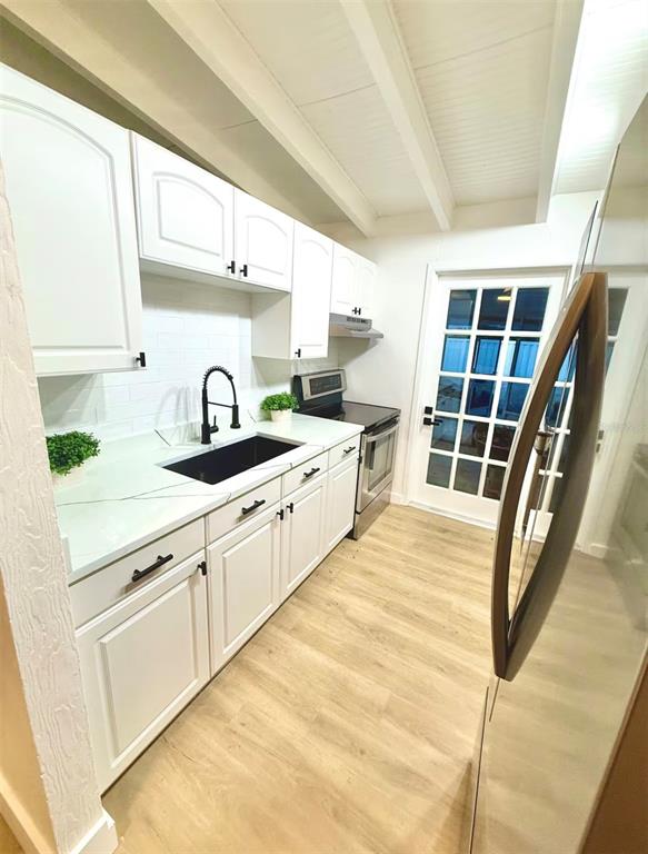 A kitchen features white cabinets, a black sink, light countertops, and wood-look flooring — 2446 SHELLEY STREET, CLEARWATER, FL