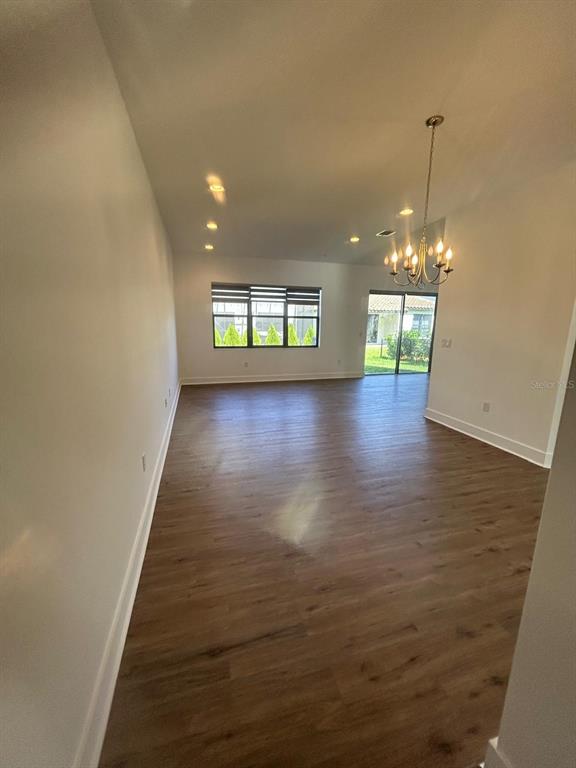 An open-concept living area features wood-look flooring, recessed lighting, a chandelier, and sliding glass doors — 5525 AGOSTINO WAY, AVE MARIA, FL