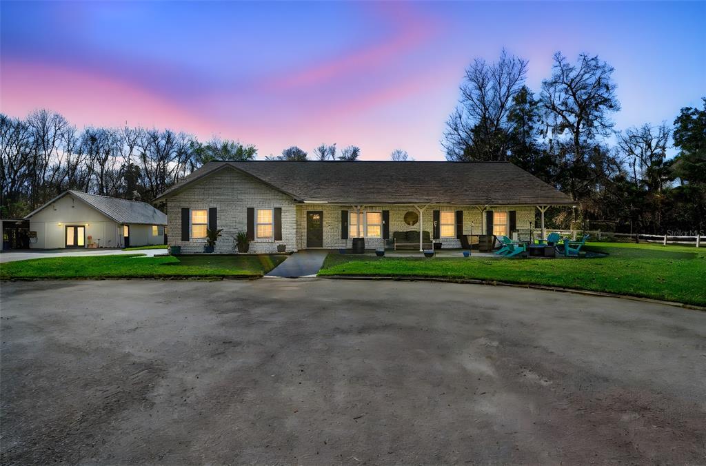 A single-story brick house with a large driveway and a detached garage at dusk — 3080 RAGIS ROAD, EDGEWATER, FL