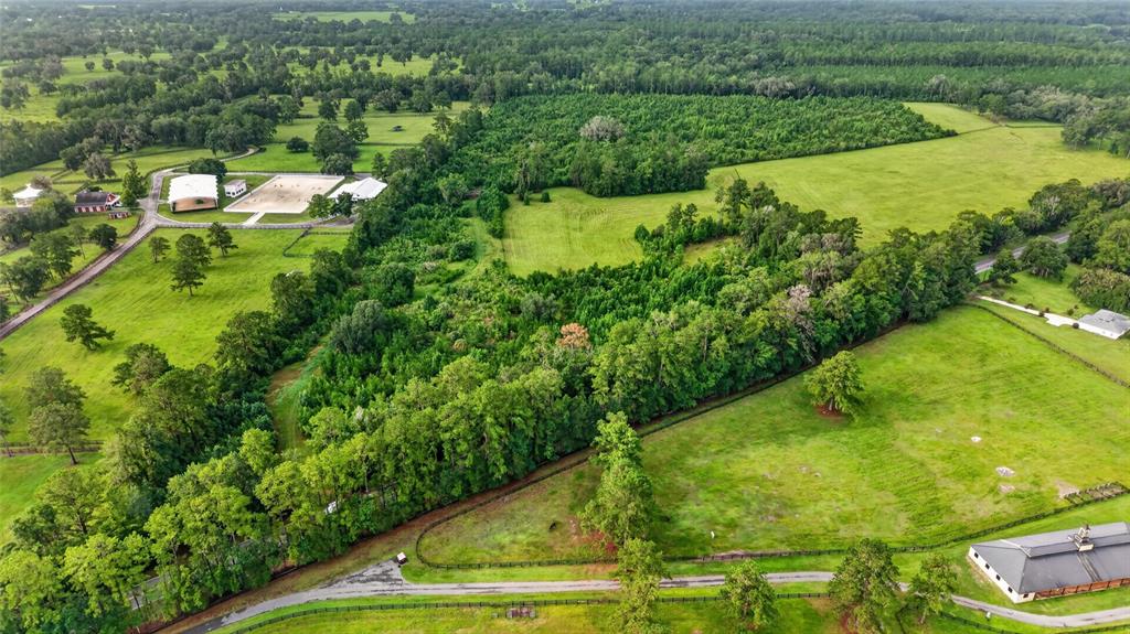 An aerial view shows a rural property with pastures, wooded areas, and equestrian facilities — 15958 W HWY 318, WILLISTON, FL