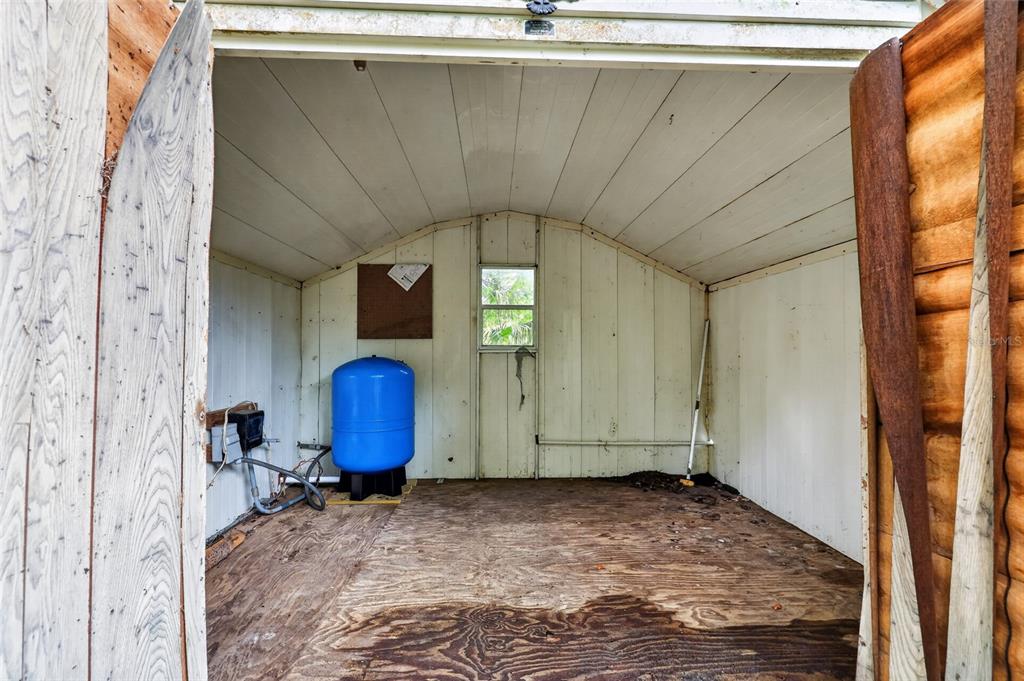 An interior view of a shed featuring a blue water pressure tank and wooden flooring — 15958 W HWY 318, WILLISTON, FL