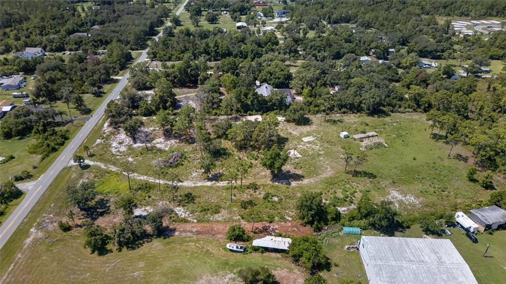 An aerial view shows a large, partially wooded vacant lot next to a paved road — 2670 MCMICHAEL ROAD, ST CLOUD, FL