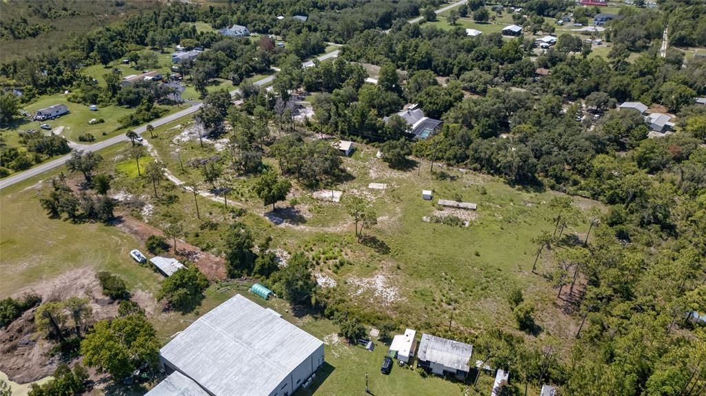 An aerial view shows a large, grassy lot with scattered trees and several small structures — 2670 MCMICHAEL ROAD, ST CLOUD, FL
