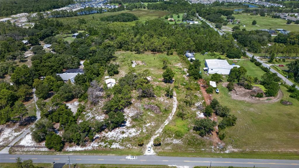 An aerial view shows a large, partially wooded lot with a white building and driveway — 2670 MCMICHAEL ROAD, ST CLOUD, FL