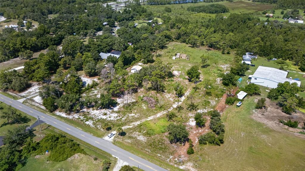 An aerial view shows a vacant, partially wooded lot situated next to a paved road — 2670 MCMICHAEL ROAD, ST CLOUD, FL