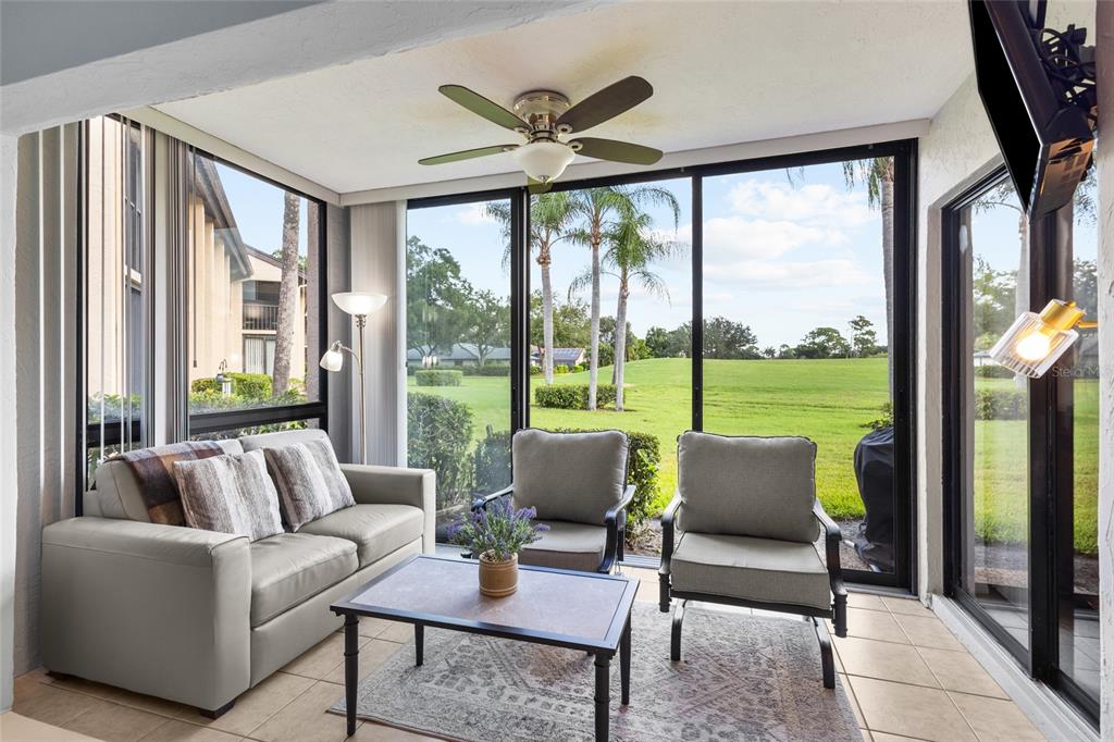 A sunroom with tile floors, a ceiling fan, and a view of a grassy golf course — 6211 TIMBER LAKE DRIVE UNIT B1, SARASOTA, FL