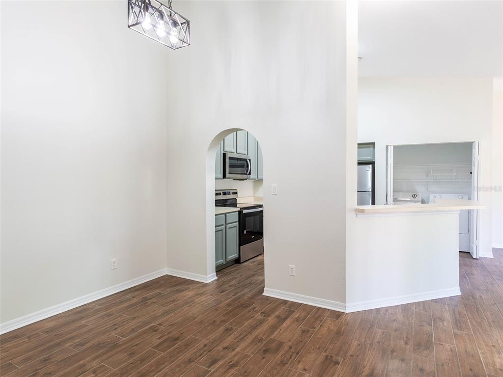 A dining area with wood-look tile flooring leads through an arched doorway to a kitchen — 36921 VALUE CIRCLE, DADE CITY, FL