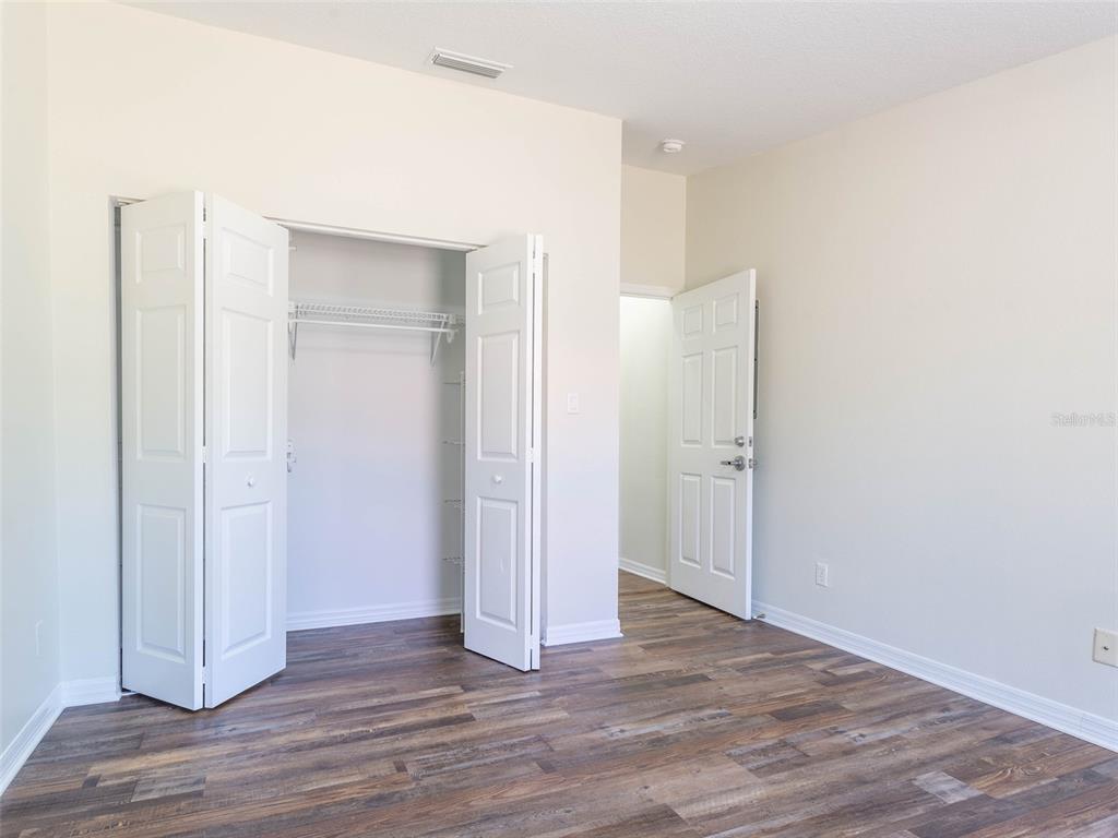 An empty room features wood-look flooring, a white closet with bi-fold doors, and a doorway — 36921 VALUE CIRCLE, DADE CITY, FL