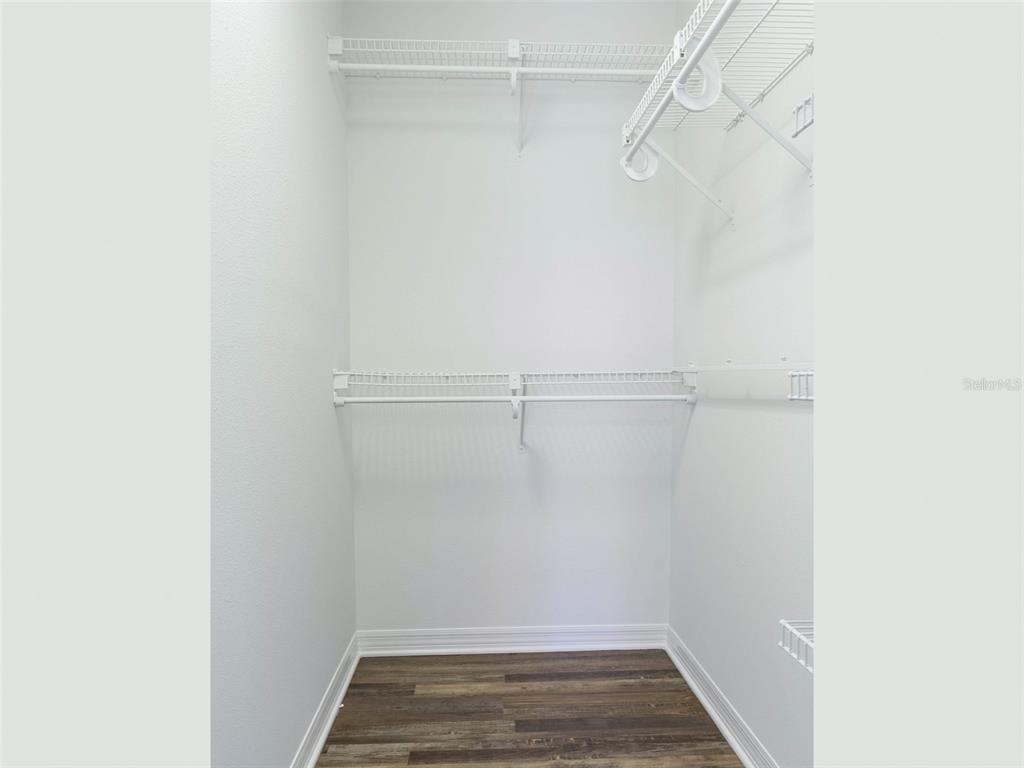 A walk-in closet features white wire shelving and wood-look flooring — 36921 VALUE CIRCLE, DADE CITY, FL