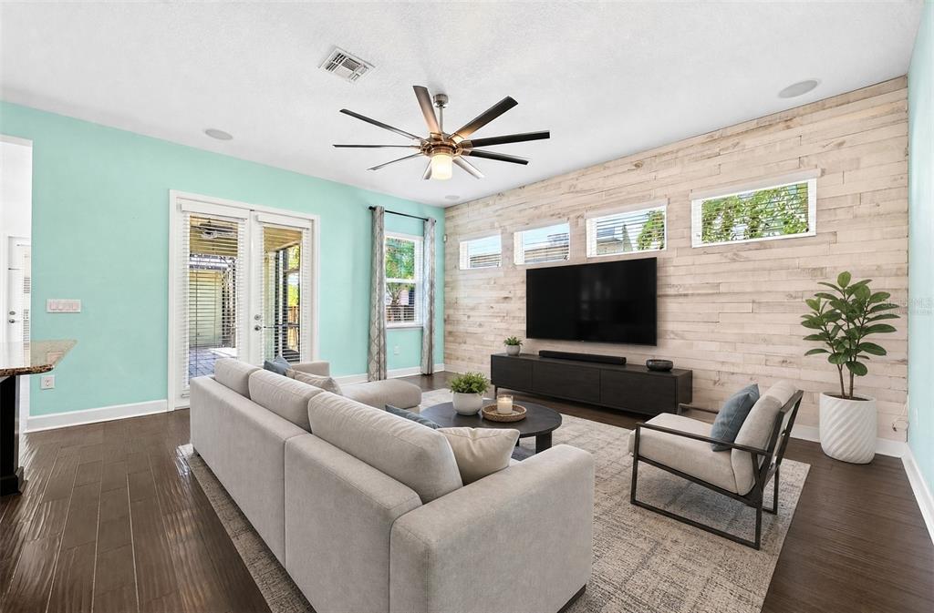 A living room features a light-colored sectional sofa, wood-paneled accent wall, and mint-colored walls — 8130 LAUREATE BOULEVARD, ORLANDO, FL
