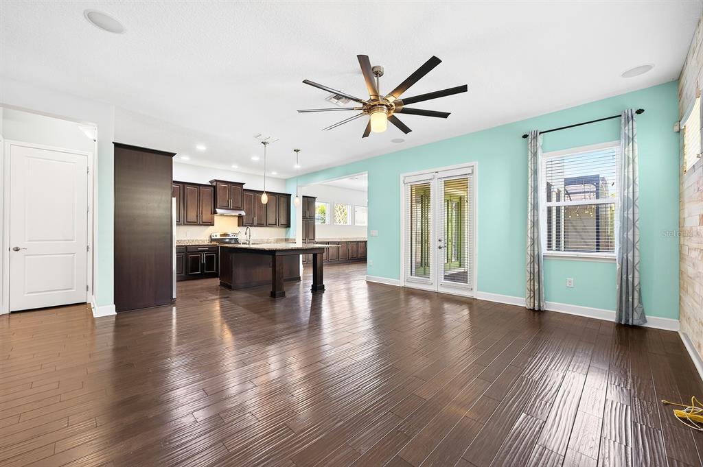 A spacious open-concept living area features dark wood floors, a kitchen island, and turquoise walls — 8130 LAUREATE BOULEVARD, ORLANDO, FL