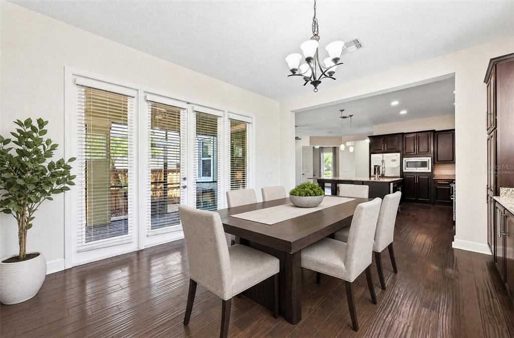 A dining room with a wooden table, six chairs, and an open view into the kitchen — 8130 LAUREATE BOULEVARD, ORLANDO, FL