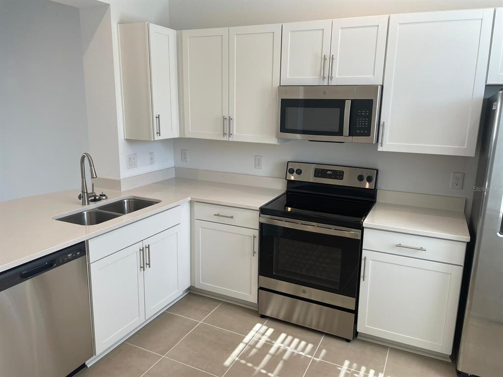 A kitchen with white cabinets, stainless steel appliances, and light-colored countertops — 6330 FAIRMONT LANE, PALMETTO, FL