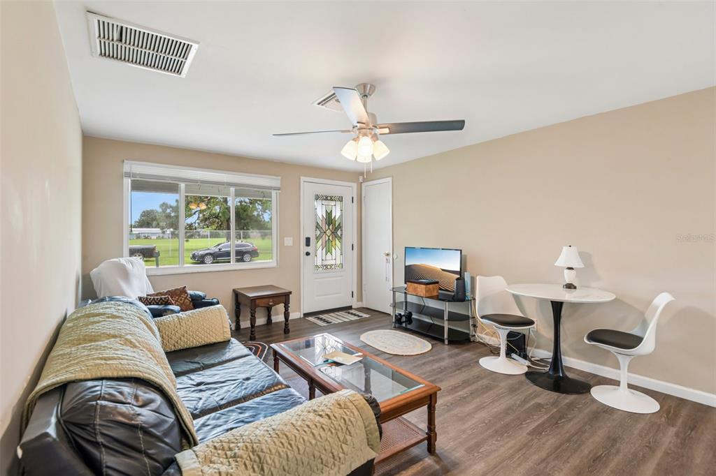 A living room features a sofa, a glass coffee table, a dining set, and a door — 8401 PORTULACA AVENUE, SEMINOLE, FL