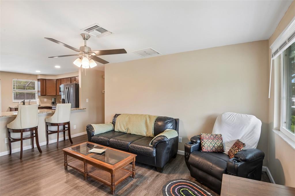A living room with dark leather furniture, a wooden coffee table, and an open kitchen — 8401 PORTULACA AVENUE, SEMINOLE, FL