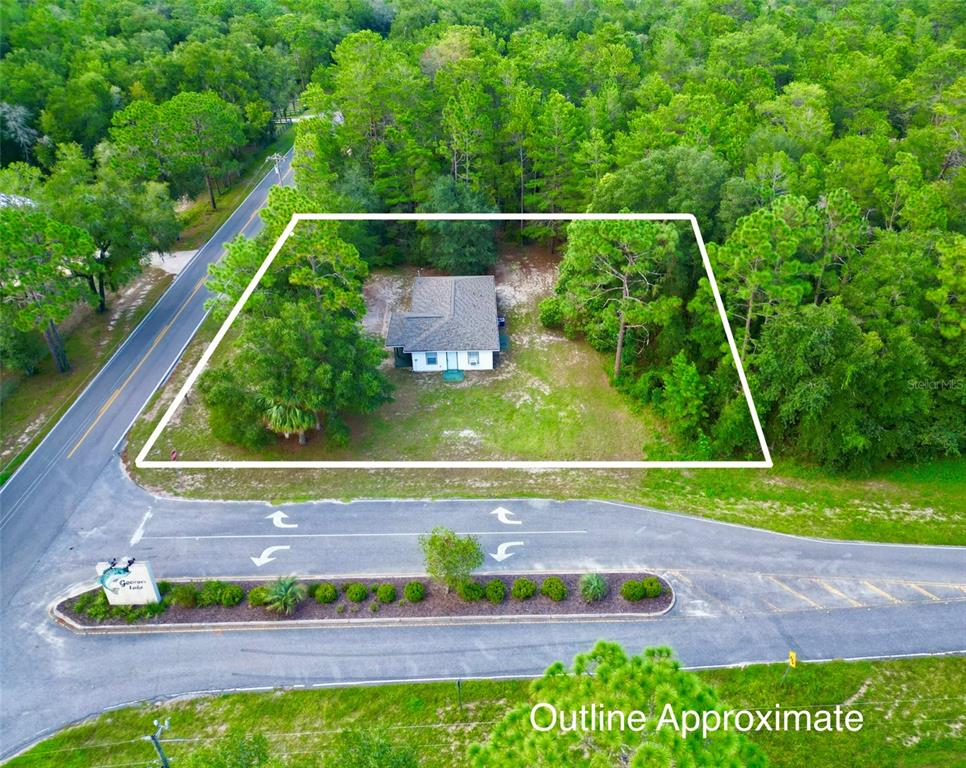 An aerial view shows a single-story house situated on a wooded lot near a road — 1150 CORAL FARMS ROAD, FLORAHOME, FL