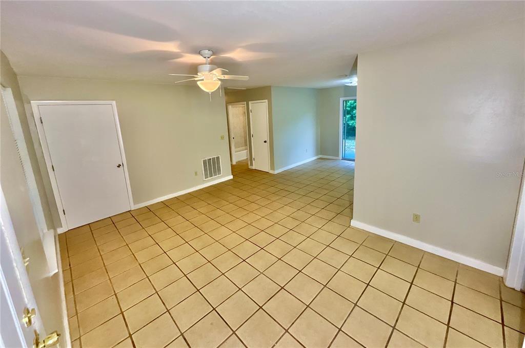 An interior room with beige walls, tiled flooring, a ceiling fan, and multiple doorways — 1150 CORAL FARMS ROAD, FLORAHOME, FL