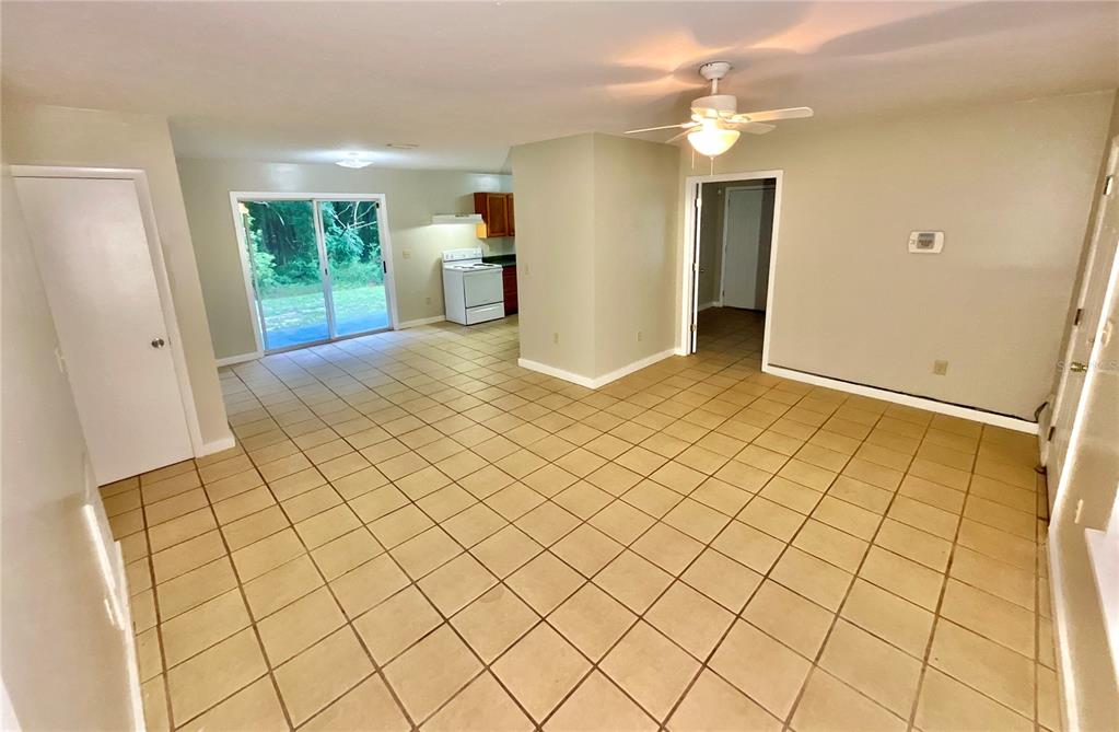 An open-concept living and dining area features beige tile flooring and a ceiling fan — 1150 CORAL FARMS ROAD, FLORAHOME, FL