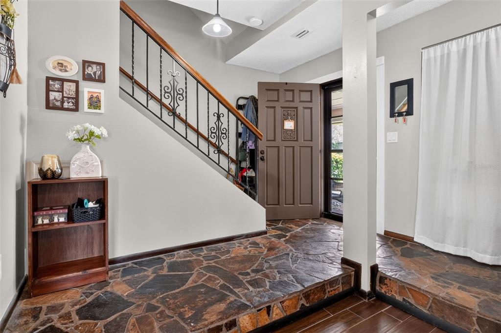 An entryway features a stone floor, a wooden staircase with iron railings, and a brown door — 2 TIMBERLINE TRAIL UNIT B, ORMOND BEACH, FL