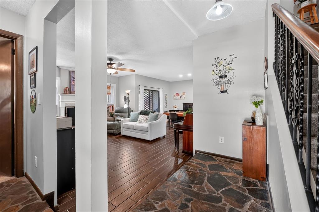 An entryway with stone flooring leads into a living room with wood-look tile floors — 2 TIMBERLINE TRAIL UNIT B, ORMOND BEACH, FL