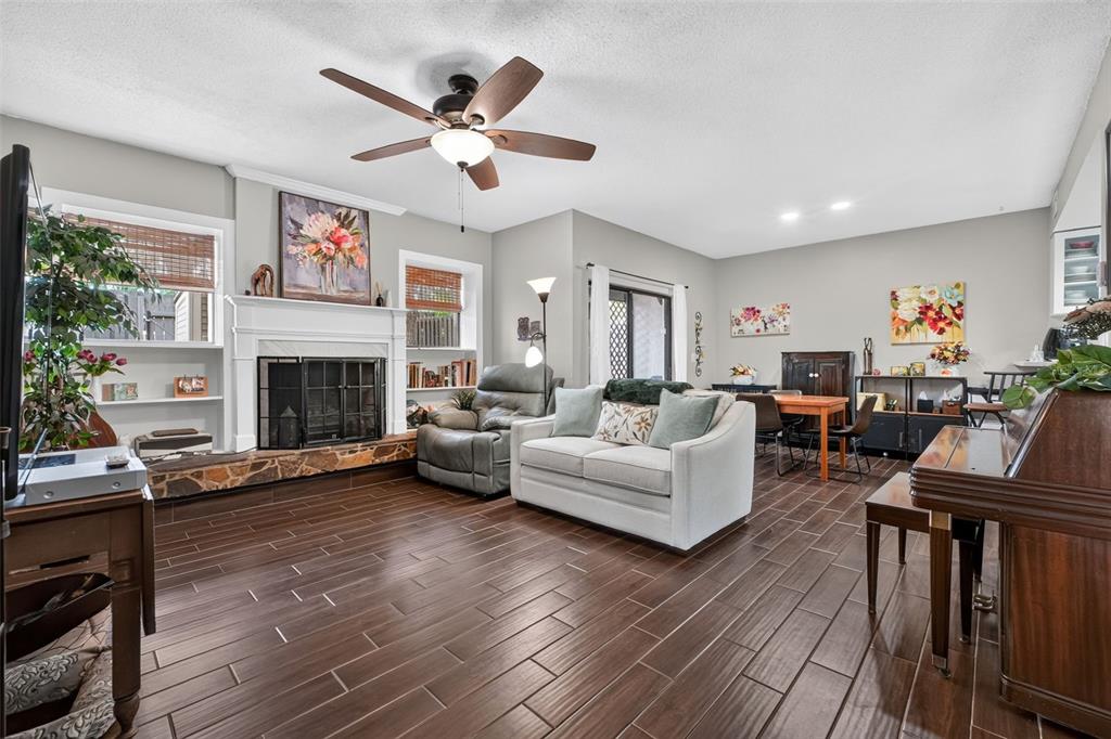 A living room features a stone fireplace, wood-look tile flooring, and a ceiling fan — 2 TIMBERLINE TRAIL UNIT B, ORMOND BEACH, FL