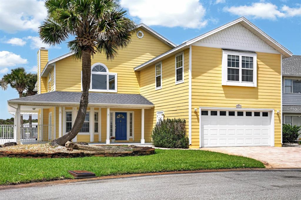 A two-story yellow house with a blue front door, a garage, and a palm tree — 9277 JULY LANE, ST AUGUSTINE, FL