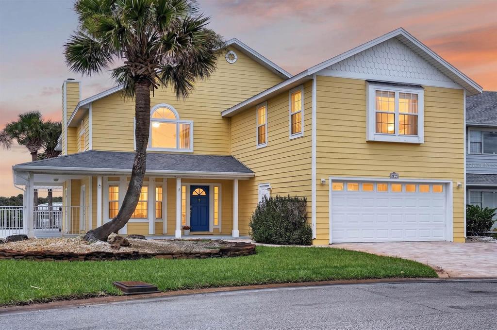 A two-story yellow house with a white garage, a front porch, and a palm tree — 9277 JULY LANE, ST AUGUSTINE, FL