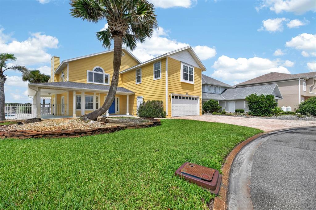 A yellow two-story house with a palm tree, a paved driveway, and a green lawn — 9277 JULY LANE, ST AUGUSTINE, FL
