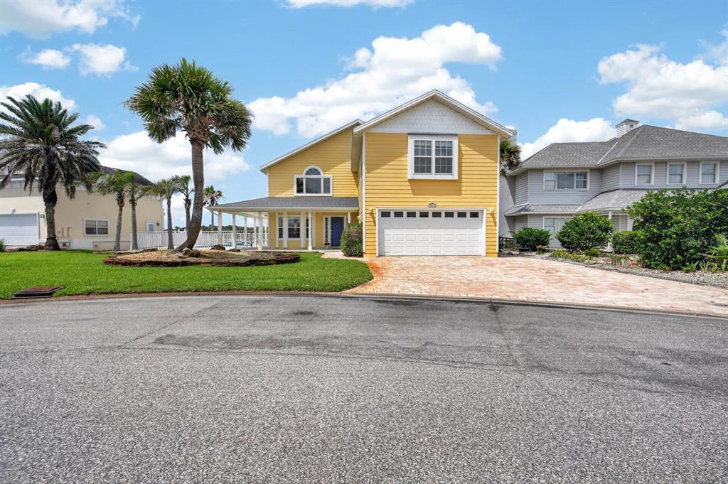 A yellow two-story house with a white garage and a palm tree in the yard — 9277 JULY LANE, ST AUGUSTINE, FL