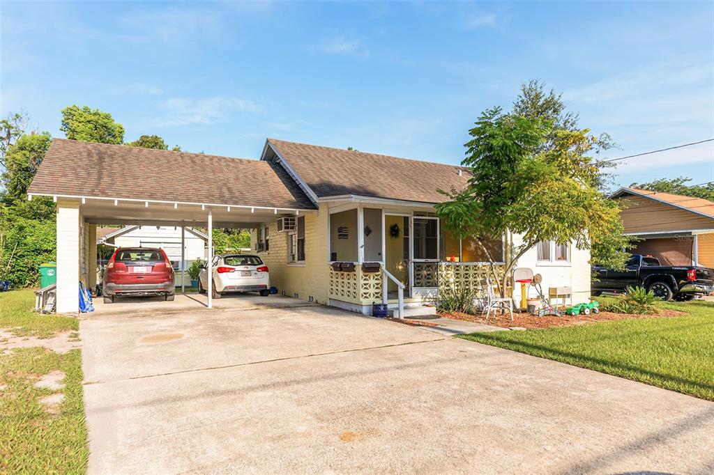 A single-story house with a carport, a screened front porch, and a concrete driveway — 220 N ADELLE AVENUE, DELAND, FL