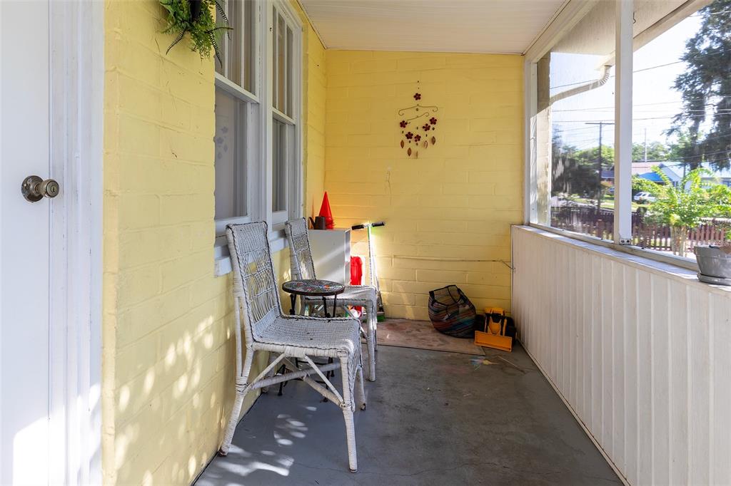 A screened-in porch features yellow painted brick walls, a gray floor, and two white chairs — 220 N ADELLE AVENUE, DELAND, FL