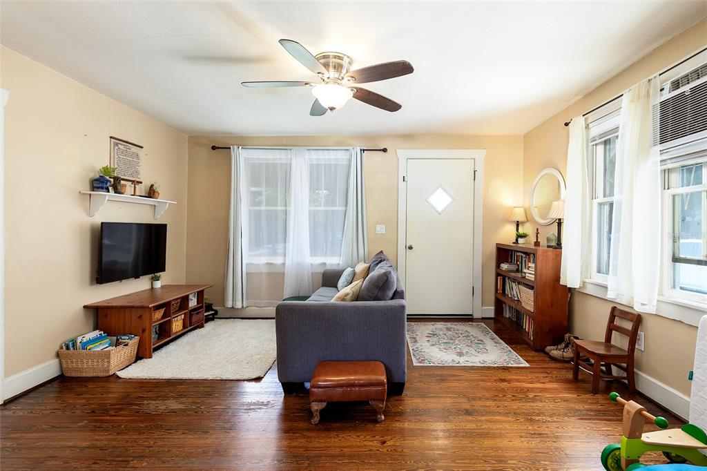 A living room features hardwood floors, a gray sofa, a television, and a ceiling fan — 220 N ADELLE AVENUE, DELAND, FL