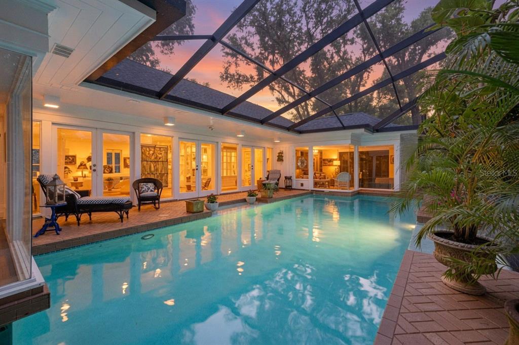 A screened-in swimming pool patio features brick decking and multiple glass doors leading indoors — 602 S RIVERHILLS DRIVE, TEMPLE TERRACE, FL