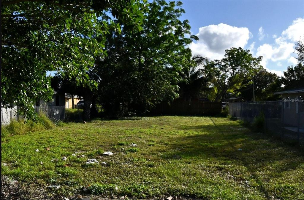 A vacant, grassy residential lot is enclosed by chain-link fencing and surrounded by mature trees — EDGEWOOD TERRACE, FORT PIERCE, FL