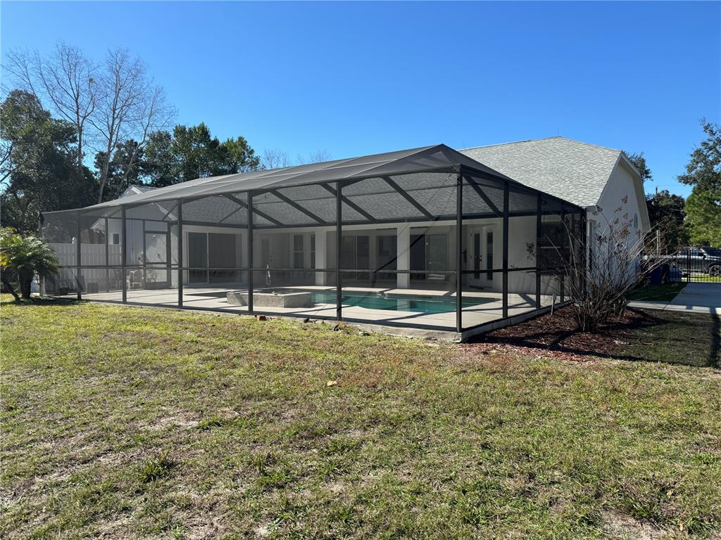 A backyard view of a house with a screened-in pool and patio area — 7565 JOMEL DRIVE, WEEKI WACHEE, FL
