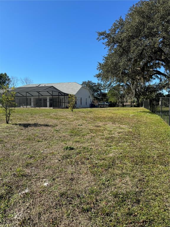A view of a house with a screened-in pool enclosure and a large grassy yard — 7565 JOMEL DRIVE, WEEKI WACHEE, FL