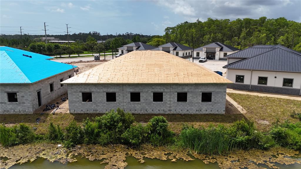 An aerial view shows several newly constructed buildings with dark metal roofs near a pond — 40 EXCHANGE LOOP LOOP UNIT 6, PALM COAST, FL