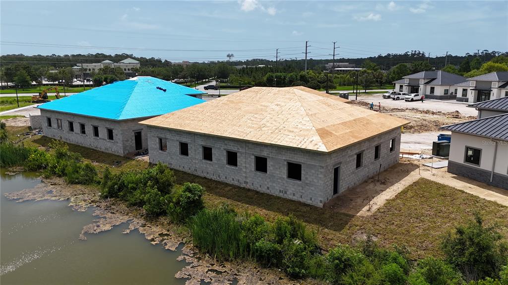 An aerial view shows two newly constructed commercial buildings with dark metal roofs near water — 40 EXCHANGE LOOP LOOP UNIT 6, PALM COAST, FL