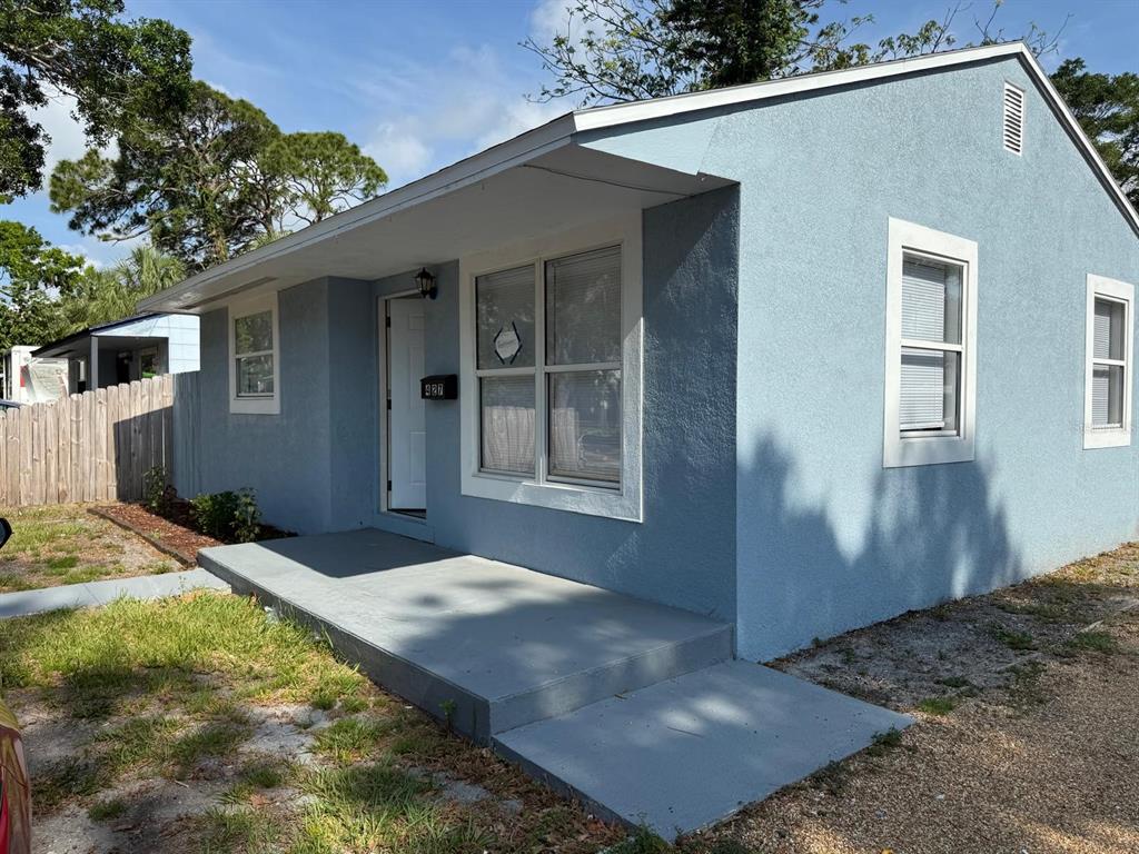 A light blue, single-story house features a concrete porch and white-trimmed windows — 427 40TH AVENUE S, ST PETERSBURG, FL