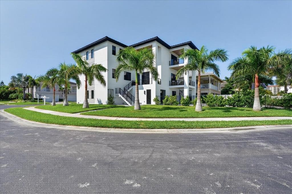 A three-story white residential building with palm trees and a lawn in the foreground — 116 WIMBLEDON COURT, REDINGTON SHORES, FL