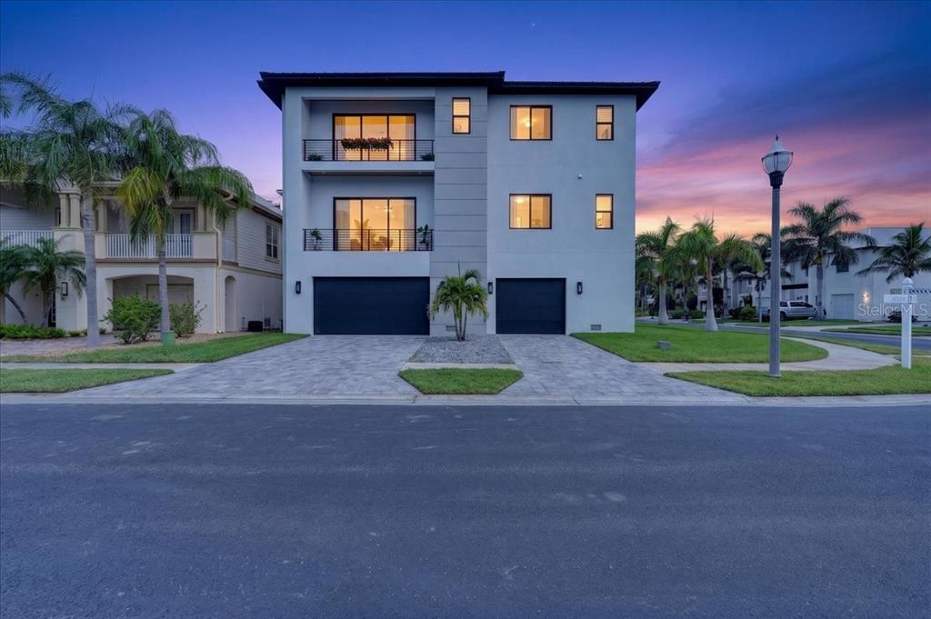 A three-story modern house with two garages and balconies sits behind a paved driveway — 116 WIMBLEDON COURT, REDINGTON SHORES, FL