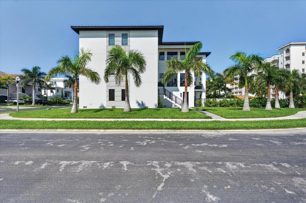 A modern white three-story building stands behind a grassy lawn with several palm trees — 116 WIMBLEDON COURT, REDINGTON SHORES, FL